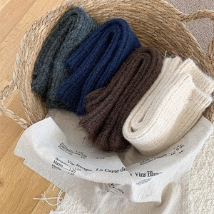 Close-up of thick ribbed knit scarves in multi-colors inside a vintage woven basket