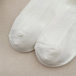 Close-up of white knit crew socks showing ribbed texture and fine stitching detail