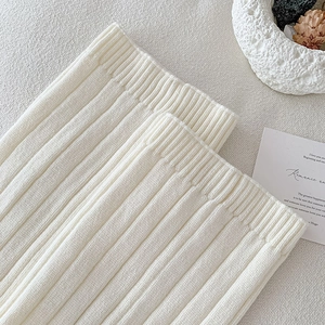 Detailed close-up of cream knit leg warmer featuring vertical ribbed texture and cuff detail