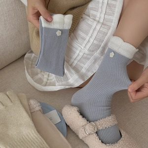 Detail of blue ribbed crew socks with white lace trim and embroidered flower accent