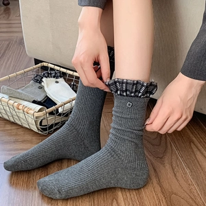 Close-up of grey ribbed calf socks with plaid ruffle trim and metallic button detail