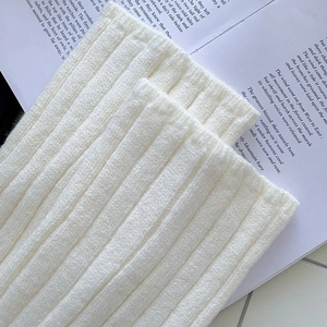 Detail shot of white ribbed knit leg warmers with thick plush texture and soft vertical stripes