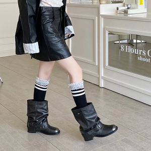 Detail of black calf socks with white lace trim and stripes paired with leather boots