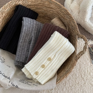 Close-up of four colors of knitted leg warmers with vertical ribs and button details