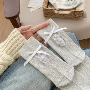 Close-up of grey mid-calf sock with white bow, heart embroidery and knit texture