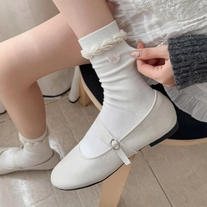 Detail of white ruffle socks featuring a cute heart button and white Mary Jane leather shoes