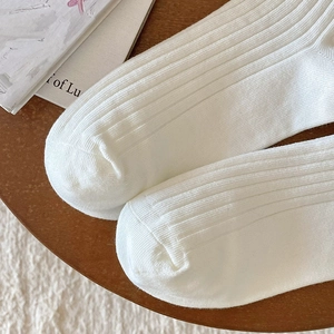 Close-up of white vertical ribbed knit socks showing high-quality stitching and cotton texture