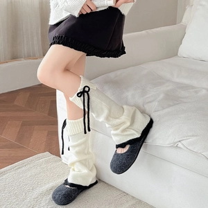 Gros plan de jambières en tricot blanc avec nœud noir et chaussures de maison confortables