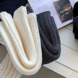 Detailed texture of thick ribbed knit leg warmers in cream and dark grey colors