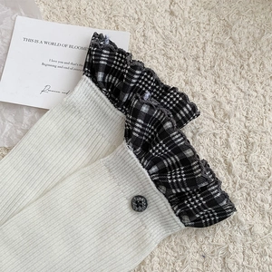 Detail of white ribbed knit socks with houndstooth ruffle trim and vintage button