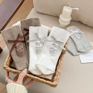 Detail of knit socks with bow ribbons and heart embroidery in a woven basket