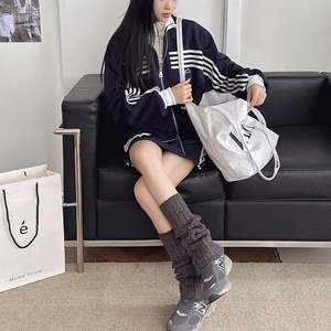 Detail showing grey knitted leg warmers paired with sneakers and a tote bag