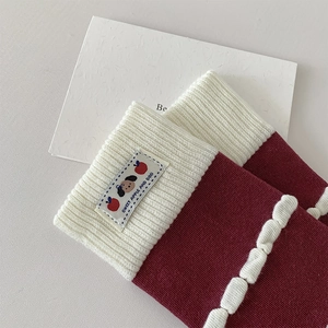 Detailed close-up of burgundy knit socks featuring a cute cartoon patch and white stitching