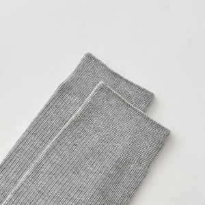 Détail rapproché des poignets en maille côtelée gris clair sur chaussettes en coton