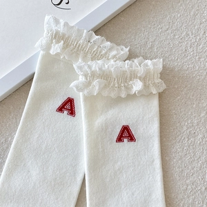 Close-up of white calf socks featuring delicate lace trim and red letter A embroidery