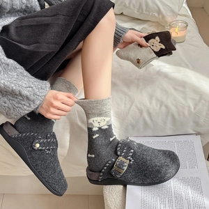 Détail de chaussettes en tricot gris avec motif chiot et chaussons en feutre pour l'hiver