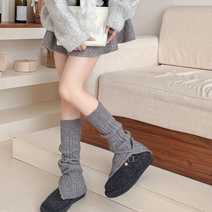 Detail of grey ribbed knit leg warmers showing thick texture and button slit design