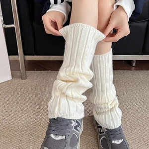 Close-up of white ribbed knit leg warmers showing soft wool texture and stacked style