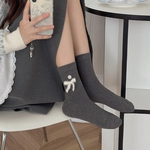 Detail of dark grey ribbed socks featuring plush white bow and floral 3D ornaments