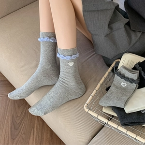 Gray crew socks with light blue ruffle trim and a heart button detail for women