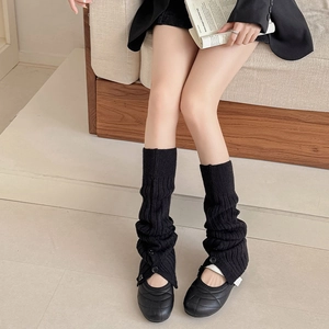 Detail of black ribbed knit leg warmers with slit design and decorative buttons
