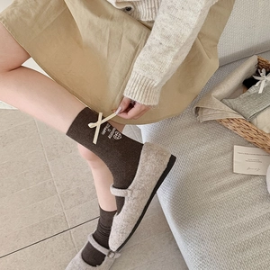 Detailed knit of dark brown socks with a beige silk bow and heart embroidery