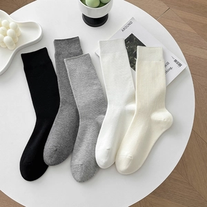 Gros plan de cinq paires de chaussettes en coton côtelé noires, grises, blanches et beige
