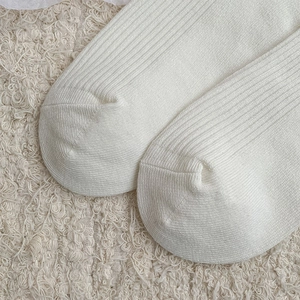 Close-up of white ribbed knit fabric texture on cotton crew socks for women