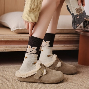 Détail de chaussettes d'hiver chaudes à motifs d'animaux et pantoufles en daim fourrées