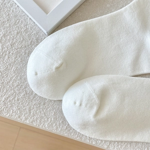 Close-up of white ribbed knit cotton socks showing flat-toe seam and fine texture