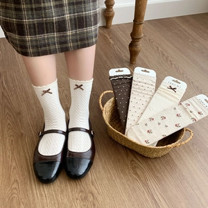 Close-up of Japanese vintage crew socks with bows, polka dots, and floral knit textures