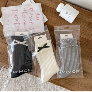 Detailed view of ruffle cuff crew socks with bows in black, white, and grey colors