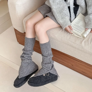 Detail of grey ribbed knit leg warmers with plush shoes and retro buckle accents