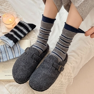 Chaussettes vintage à rayures avec mules en feutre gris dans un décor d'hiver doux
