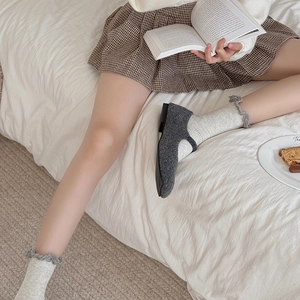 Gros plan de chaussettes beiges à côtes avec bord à volants gris et chaussures Mary Jane
