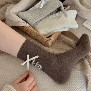 Close-up of ribbed cotton socks with bow ribbon and happiness embroidery detail