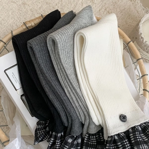 Detail of ribbed knit crew socks with plaid ruffle trim and button in a wicker basket