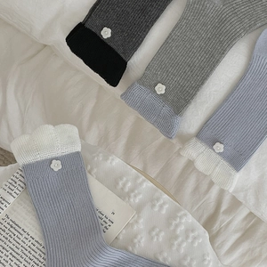 Detailed macro view of cotton rib-knit crew socks with floral button and ruffle edge