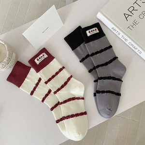 Detailed shot of knitted mid-tube socks with ruffled stripes and cute cartoon fabric patches