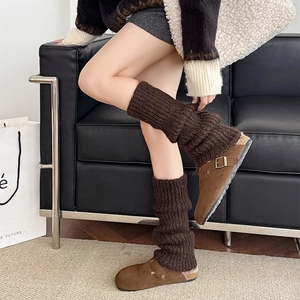 Detail of dark brown cable knit leg warmers paired with suede shearling-lined mules