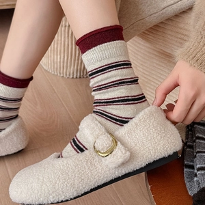 Détail de mocassins en sherpa crème avec boucle dorée et chaussettes à rayures vintage