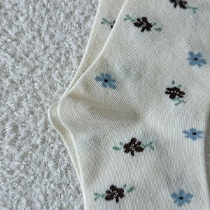 Détail de chaussettes en tricot crème avec motif floral bleu et coutures au talon