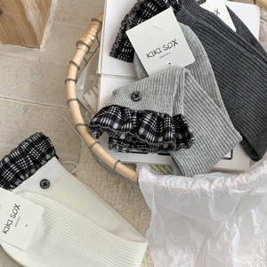 Detail of ribbed knit crew socks with checkered ruffle trim and decorative button accents
