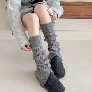 Grey knitted leg warmers with ribbed texture and side buttons for a cozy winter style