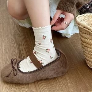 Detail of brown faux fur ballet flats with bow and floral knit socks on wooden floor