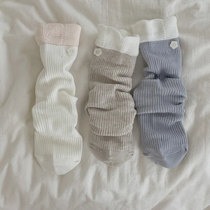 Detailed close-up of knitted mid-calf socks with floral buttons and lace trim