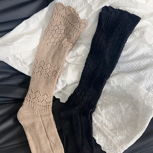 Detailed close-up of khaki and black lace-trimmed hollow knit socks in a flat lay view