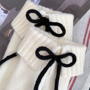 Gros plan sur jambières en tricot crème avec détails de nœuds noirs contrastés