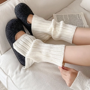 Detail of off-white ribbed knit leg warmers paired with gray Mary Jane slippers
