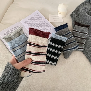 Détail de chaussettes en maille à rayures colorées avec bords roulés sur une surface